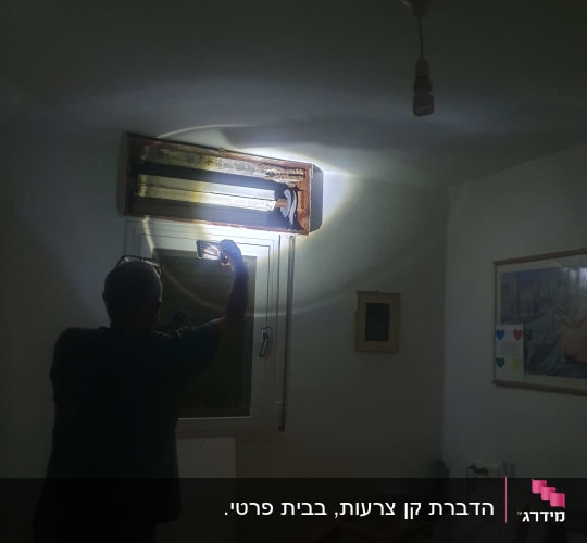 אדם בודק מזגן עם פנס בחדר חשוך
